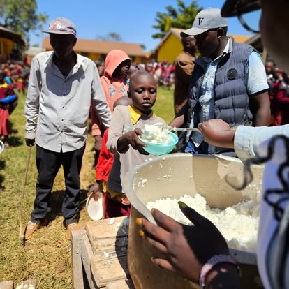 A child receiving a warm meal at a Lishe Kwa Mtoto feeding day